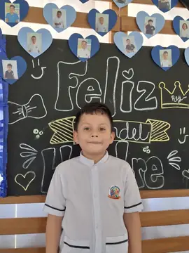 Estudiante con guayabera del uniforme frente al tablero de Feliz Día del Hombre