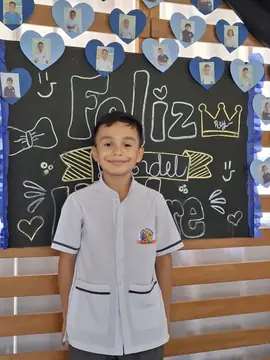 Estudiante con uniforme de diario frente al tablero de Feliz Día del Padre