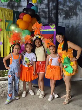 Estudiantes y docente con vestuario naranja en una muestra artística del colegio
